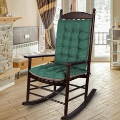 a rocking chair with a green cushion on top of it in front of a fireplace