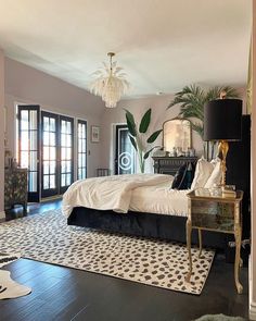 a bedroom with black and white decor, large bed, chandelier, and two windows