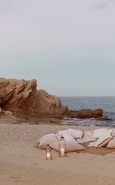 two lanterns are sitting on the beach next to pillows