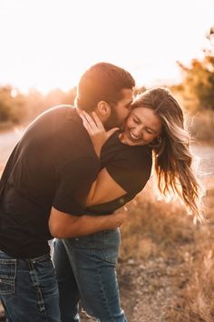 a man and woman embracing each other in the middle of an open field at sunset