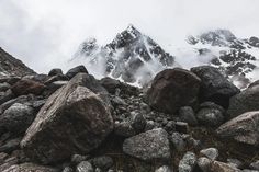 rocks and boulders on the side of a mountain with snow capped mountains in the background