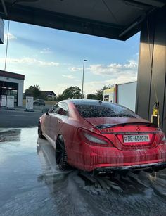 a red car is parked in the middle of a flooded gas station with water all over it