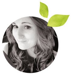 a black and white photo of a woman with green leaves on it's head