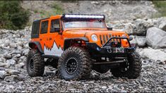 an orange jeep is parked on some rocks