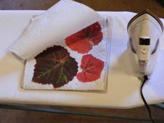 an ironing board with leaves on it next to a towel and a hair dryer