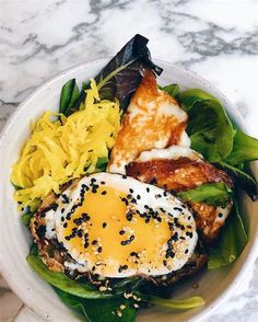 a white bowl filled with food on top of a marble countertop next to a knife and fork