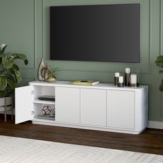 a white entertainment center with a flat screen tv mounted on the wall and candles in front of it