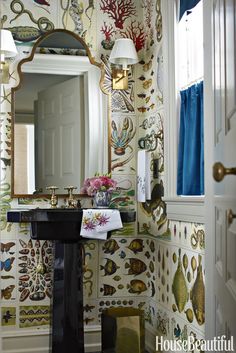 the bathroom is decorated with colorful wallpaper and gold accents, along with an ornate mirror