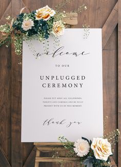 an unplugged ceremony sign with flowers and greenery sits on a wooden table