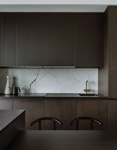 a kitchen with wooden cabinets and marble counter tops, along with two chairs in front of the sink