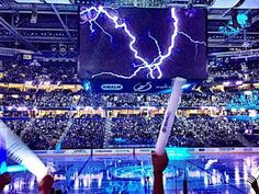 the inside of an arena with people playing video games and lightning in the sky above