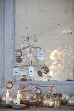 a small christmas tree sitting on top of a wooden table next to candles and ornaments