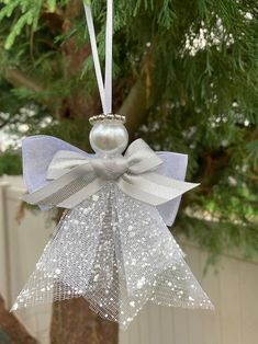 a christmas ornament hanging from a tree with a bow and pearls on it