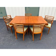 a wooden table with six chairs around it and a wall in the backround