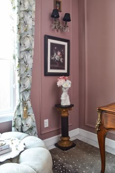 a living room with pink walls and white flowers in vases on the end table