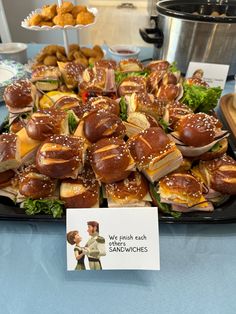 a table topped with lots of sandwiches covered in cheese and toppings next to a sign that says we finish each sandwich sandwiches