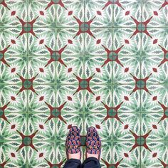 a person standing in front of a green and red tile wall with their feet up