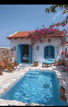 an outdoor swimming pool next to a house with flowers growing on the roof and windows