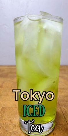 a tall glass filled with ice tea sitting on top of a wooden table