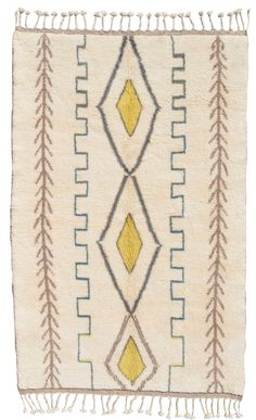 a white rug with yellow and blue designs on the front, fringes hanging down from it