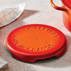 an orange frisbee sitting on top of a table next to a tea pot