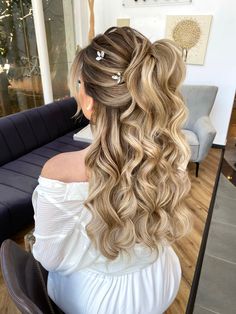 a woman sitting in a chair with long blonde hair styled into a half updo