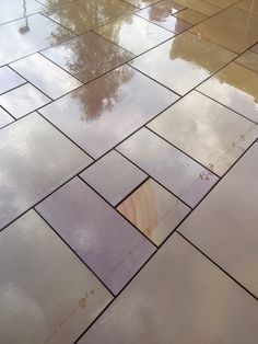 an umbrella sitting on top of a tiled floor next to a puddle in the rain