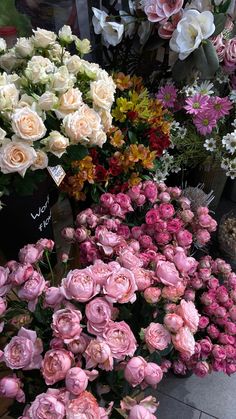 many different types of flowers on display in a flower shop, including pink and white roses