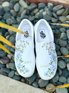 a pair of white shoes sitting on top of a pile of rocks next to plants