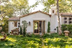 a white house sitting in the middle of a lush green field