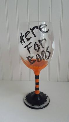 a wine glass with writing on it sitting on a table next to a white wall