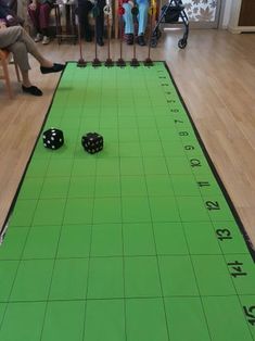 two black dices on a green mat with people in the background