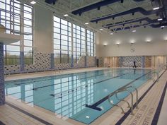 an indoor swimming pool with tiled walls and flooring in the middle, surrounded by large windows