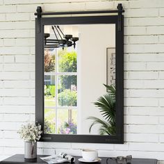 a mirror on the wall above a table with a coffee cup and plant in front of it