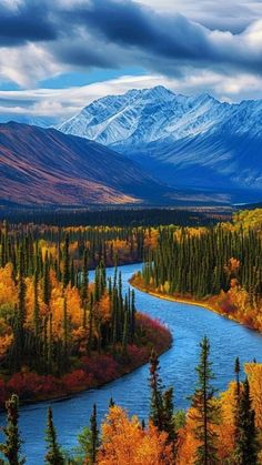 a river surrounded by trees and mountains under a cloudy sky with snow capped mountains in the distance