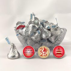 a bowl filled with silver and red candies next to two small round chocolates