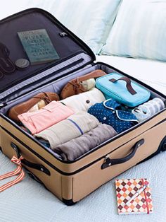 an open suitcase sitting on top of a bed filled with clothes and luggage bags next to a pillow