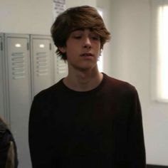 a young man standing in front of lockers with his eyes closed and one hand on his hip