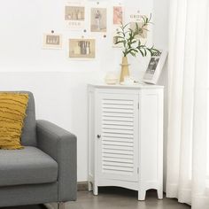 a small white cabinet next to a gray couch