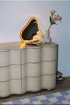 a dresser with a mirror and vase on top of it next to a flower pot