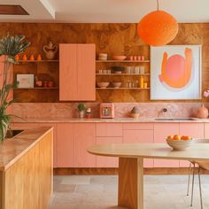 a kitchen with pink cabinets and an orange ball hanging above the countertop, along with a wooden dining table