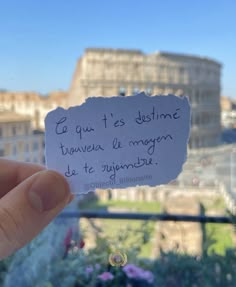 someone holding up a piece of paper that has been written on it in front of a cityscape