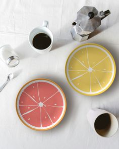 two plates with slices of grapefruit on them next to a cup of coffee