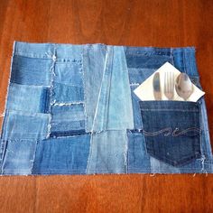 an old pair of jeans is folded into a patchwork placemat with a spoon and fork in it