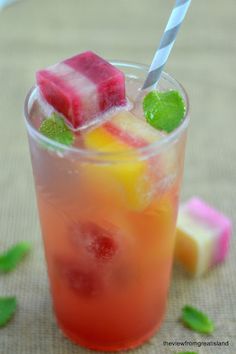 a glass filled with fruit and ice on top of a table