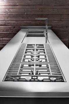 a stainless steel kitchen sink in front of a wooden wall