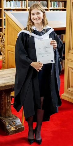 a woman in a graduation gown holding up a piece of paper