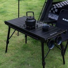 two camping tables with pots and pans sitting on top of them in the grass