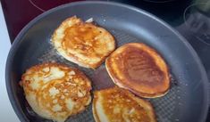 four pancakes being cooked in a frying pan