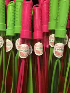 several green and pink straws are lined up in a row with tags on them